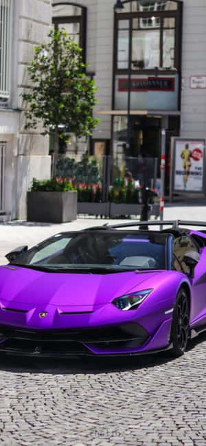 紫色藍寶堅尼 Aventador 停泊在現代建築附近的鵝卵石街道上。 — Galaxy F16 壁紙
