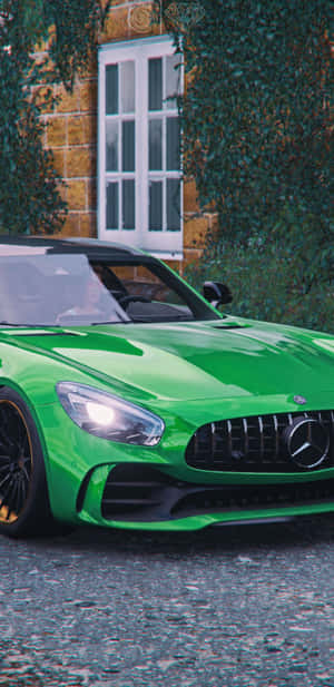 充滿活力的綠色 Mercedes-AMG GT 停在爬滿常春藤的石頭建築旁。 — Pixel 4 壁紙