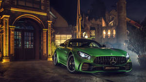 綠色 Mercedes-AMG GT 夜間停在一座石建築前，帶有溫暖燈光。