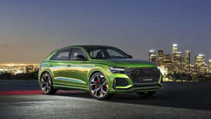 綠色Audi SQ8 Sportback停在山坡上，俯瞰夜晚燈火通明的城市。 — 攀爬 壁紙