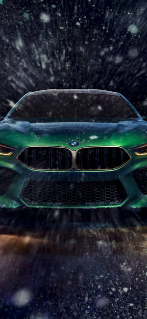 綠色BMW跑車在夜間大雪中行駛，車頭燈閃閃發光。 — iPhone 18 壁紙