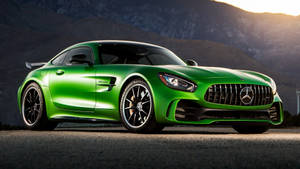 綠色Mercedes-AMG GT跑車停在日落時分的山間道路上。 — 翡翠綠 壁紙