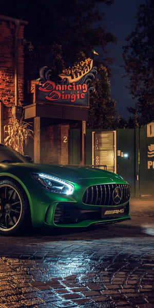 綠色Mercedes-AMG在夜間停在霓虹燈下濕漉漉的鵝卵石街道上。 — 翡翠綠 壁紙
