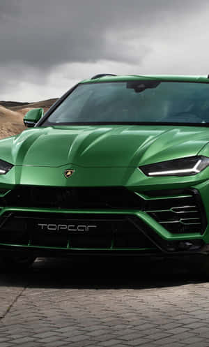 綠色藍寶堅尼 Urus SUV 停放在暴風雨天空下的鵝卵石路上 — Tecno Megapad Pro 壁紙