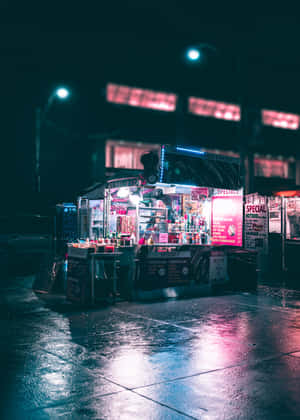 夜晚潮濕的城市街道上，一輛燈光明亮的美食車，帶有霓虹反射。 — OnePlus Pad 壁紙