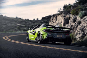 萊姆綠色McLaren跑車在日落時分行駛在山路上。 — Surface Pro 壁紙