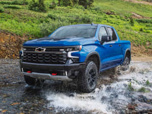 藍色 Chevrolet Silverado 卡車在森林覆蓋的山區行駛穿過淺岩石溪流。 — 雪佛蘭 壁紙