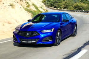 藍色Acura轎車在彎曲的山路上行駛，兩旁是綠色的山坡。 — Acura 壁紙