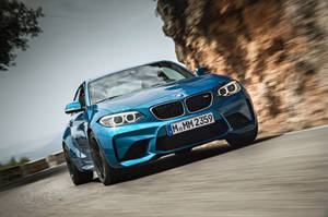 藍色BMW M2 Coupe在山路上疾馳，帶有模糊動態效果。 — Mercedes Benz C300 壁紙
