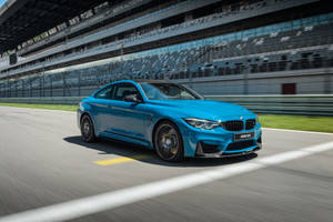 藍色BMW M4在賽道上疾馳，背景有看台。