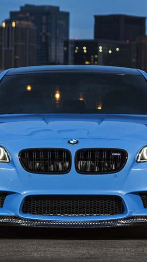 藍色BMW M5跑車停放在黃昏的城市天際線前。 — BMW iPhone 壁紙