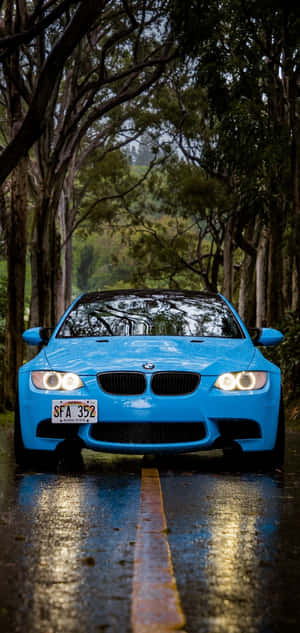 藍色BMW汽車在濕潤的森林道路上，車頭燈亮著 — S24 Ultra 壁紙