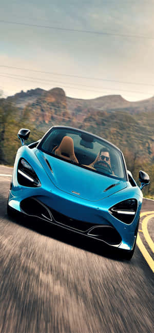 一輛藍色McLaren跑車在山路上疾馳，司機戴著太陽眼鏡。 — Pixel 7 Pro 壁紙