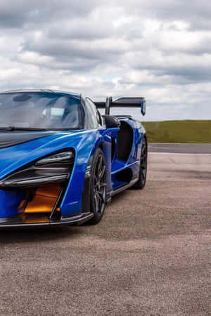 藍色McLaren Senna超級跑車在多雲天空下的瀝青賽道上 — 好看汽車 壁紙