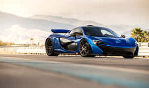 藍色McLaren P1超級跑車在沙漠公路上，背景有山脈和棕櫚樹，夕陽西下。 — 好看汽車 壁紙