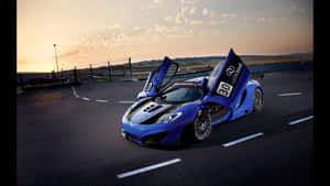 日落時分，藍色McLaren跑車在賽道上敞開車門。 — 汽車 壁紙
