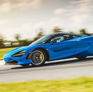 一輛藍色McLaren 720S在道路上疾馳，背景模糊。 — 麥拉倫 壁紙
