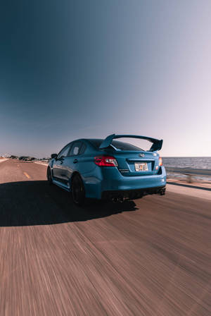 藍色Subaru WRX STI在日落時分於海岸高速公路上奔馳 — 昴 壁紙