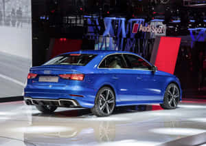 藍色奧迪RS 3轎車在光亮的展示間地板上，後面有Audi Sport標誌。 — 凱迪拉克 壁紙