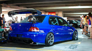 藍色改裝跑車，帶有大型後擾流板，停在地下車庫，附近有人。 — JDM風格 壁紙