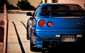 藍色日產Skyline R34跑車在日落時停放在人行道上。 — 日產GTR 壁紙