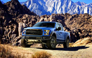 藍色福特 F-150 Raptor 卡車停放在沙漠小徑上，背景有山脈 — 老福特卡車 壁紙