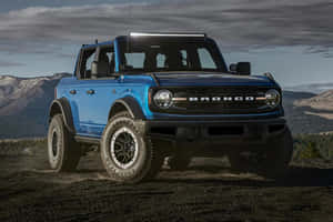 藍色福特Bronco SUV停在山附近的土路上 — 福特野馬越野車 壁紙