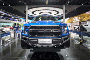 藍色福特F-150 Raptor卡車在車展上展示，地板光亮，有參觀者。 — 老福特卡車 壁紙