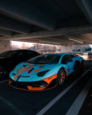 一輛青色和橙色的藍寶堅尼Aventador，在黃昏時停泊在城市高架橋下。 — 蘭博基尼 壁紙