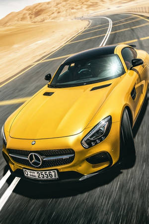 黃色 Mercedes 跑車在沙漠公路上飛馳，背景是沙丘。 — Mercedes Benz C300 壁紙