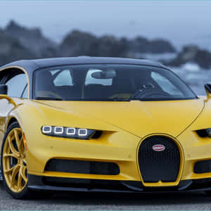 黃色Bugatti跑車停泊在海洋旁，後面有岩石峭壁。 — 布加迪 GIF 壁紙