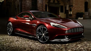 光亮的紅色Aston Martin跑車夜間停在鵝卵石街道上。 — 奧斯頓馬丁 壁紙