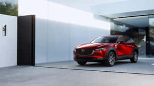 紅色Mazda CX-30 SUV停在一棟帶玻璃門的現代白色房屋前。 — 馬自達 壁紙