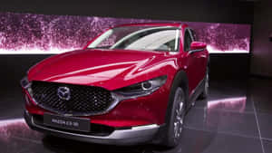 紅色Mazda CX-30 SUV在閃爍紫色背景的展廳中展示。 — 馬自達 壁紙