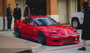 紅色馬自達RX-7跑車配備定制車身套件，停泊在城市街道上，有男子欣賞。 — 馬自達 壁紙