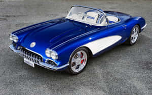 帶有白色條紋的藍色經典Corvette敞篷車停在碎石上。 — 洛米安傳奇 壁紙