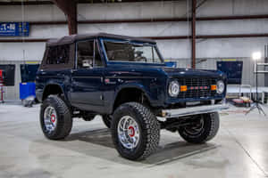 車庫工場中，一輛光澤藍色經典福特Bronco，配備鍍鉻車輪。 — 福特 壁紙