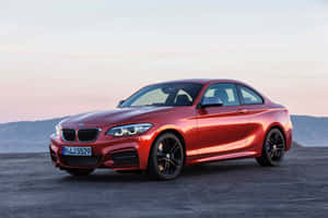 紅色BMW雙門跑車停在沙漠公路上，背景是日落時分的山脈。 — MacBook Air M4 壁紙