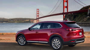 紅色Mazda CX-9 SUV停在水邊，背景有金門大橋。 — 馬自達 壁紙