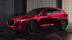 一輛紅色Mazda CX-5 SUV在工作室中，工作室有深色牆壁和反光地板。 — 馬自達 壁紙