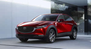 紅色Mazda CX-30 SUV停在一棟現代玻璃建築前。 — 馬自達 壁紙