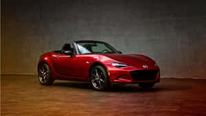 攝影棚內有紋理牆壁和溫暖燈光的紅色Mazda Miata敞篷車。 — 馬自達 壁紙