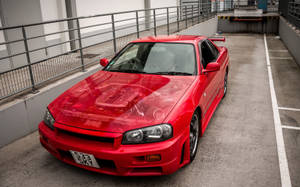 紅色日產Skyline R34停放在混凝土停車場。