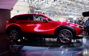 紅色馬自達CX-30 SUV在車展上展示，拋光地板上有倒影。 — 馬自達 壁紙