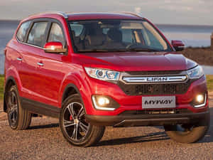 日落時停在水邊碎石上的紅色力帆Myway SUV。 — 改裝摩托車 壁紙
