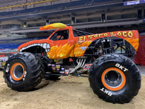 橙色怪獸卡車 El Toro Loco，帶有火焰設計和巨型輪胎，在場地中。 — 老福特卡車 壁紙