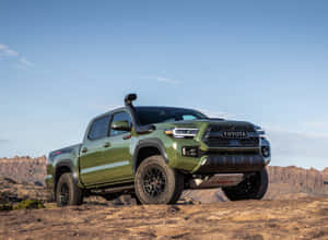 橄欖綠色的豐田Tacoma TRD Pro皮卡車在藍天下的岩石沙漠地形上。 — 豐田 壁紙