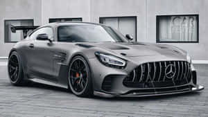 啞光灰色的 Mercedes-AMG GT R 跑車停放在現代建築物前。 — Mercedes Benz C300 壁紙