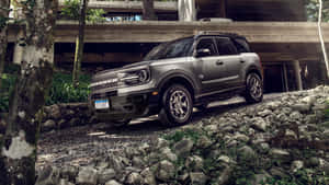 灰色福特Bronco SUV停放在現代木屋附近的岩石小徑上。 — 福特野馬越野車 壁紙