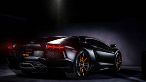 在漆黑攝影棚中，黑色藍寶堅尼 Aventador 配橙色輪圈和尾燈。 — 蘭博基尼 壁紙